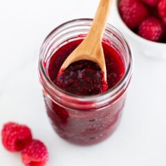 Raspberry jam in a jar with spoon.