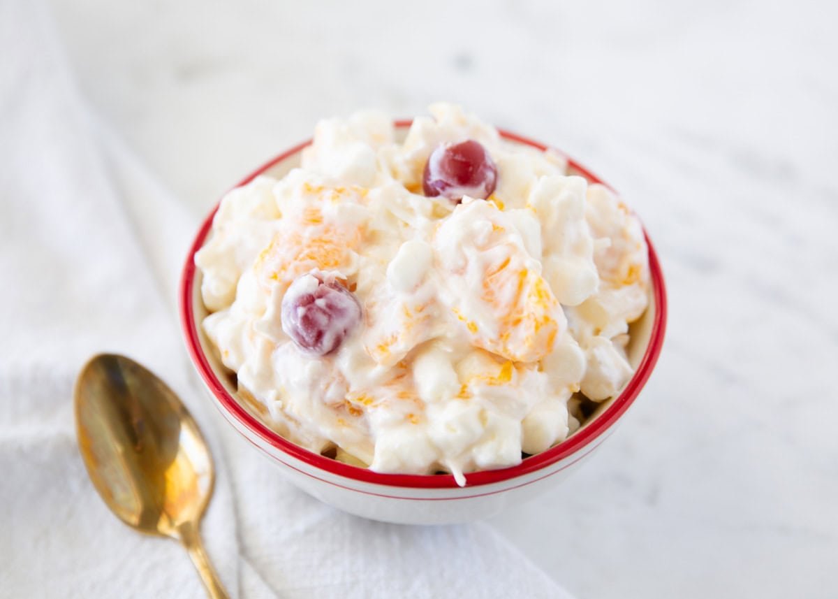 This 5 cup salad is a quick and creamy vintage fruit salad made with pineapple, mandarin oranges, marshmallows, coconut, sour cream, and maraschino cherries. A potluck favorite! Small bowl of creamy 5 cup salad with mandarin oranges, mini marshmallows, pineapple and maraschino cherries.