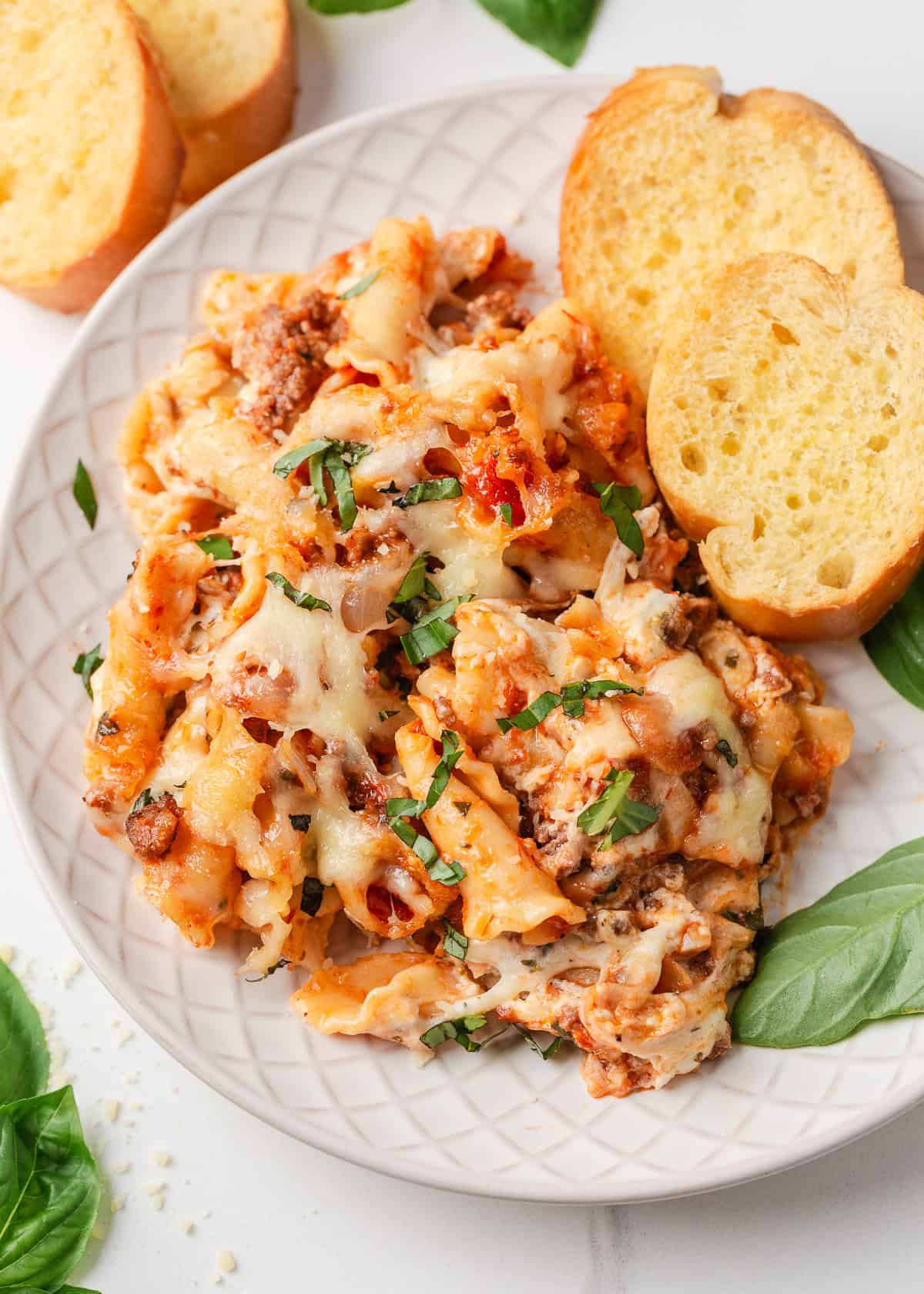 Serving of lazy lasagna casserole on a plate with toasted bread slices and fresh basil garnish.