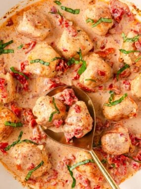 Close up picture of marry me chicken meatballs served with gold spoon.