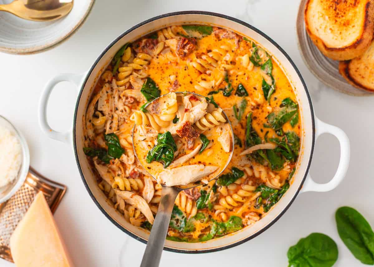 Marry me chicken soup is a cozy spin on the viral marry me chicken recipe made with tender chicken, pasta, sun-dried tomatoes and spinach in a Parmesan cream broth. A pot of marry me chicken soup with a ladle scooping up pasta, chicken, and spinach in a creamy tomato broth.