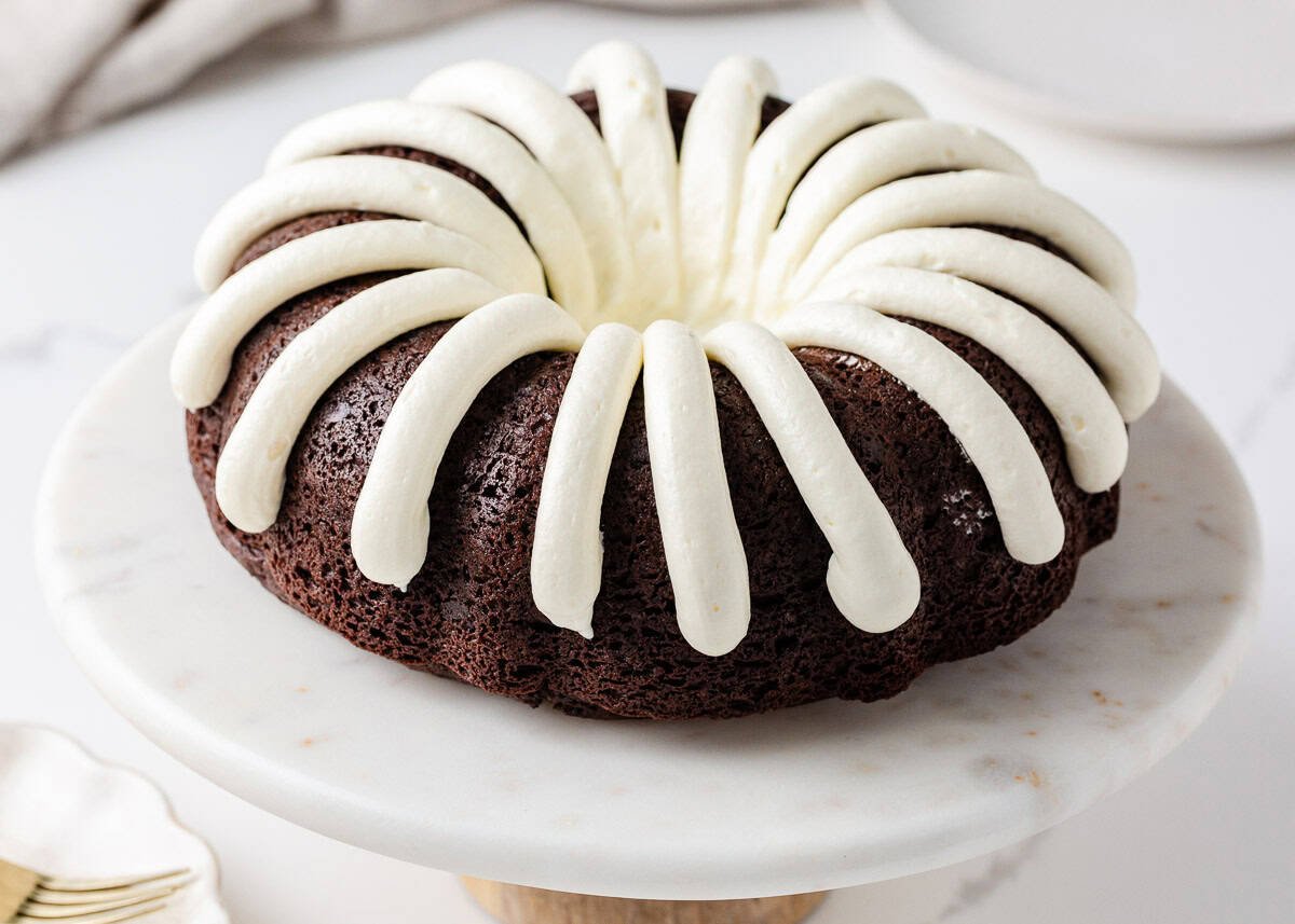 Nothing bundt cake recipe with cream cheese frosted on a cake stand.