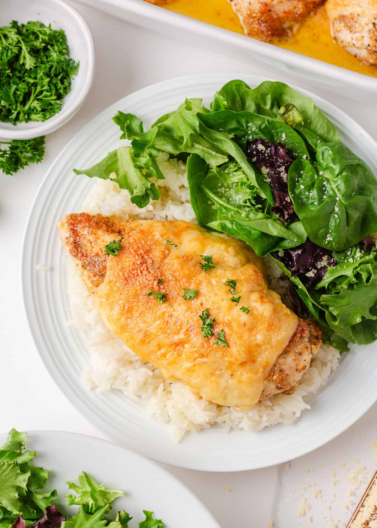 There is nothing better than Swiss chicken bake made with a handful of ingredients and a creamy, cheesy golden topping. Pair with rice and veggies, this easy dinner is served! A serving of creamy Swiss chicken over white rice on a plate with a fresh green salad on the side.