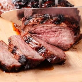Tri tip being cut on a cutting board.