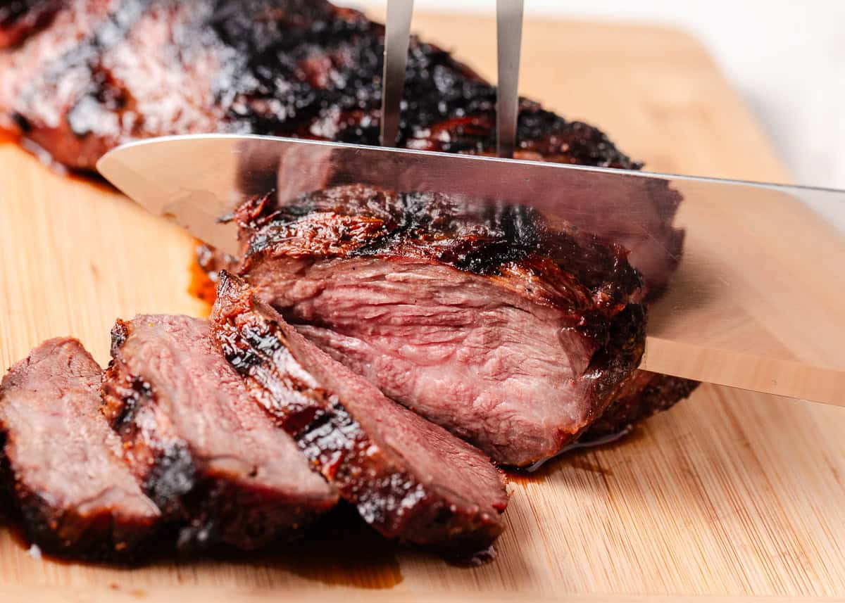 With just a simple marinade, learn how to cook tri tip on the grill or in a smoker for an unforgettable steak dinner that's juicy, tender and beefy! Tri-tip beef being sliced on a cutting board.