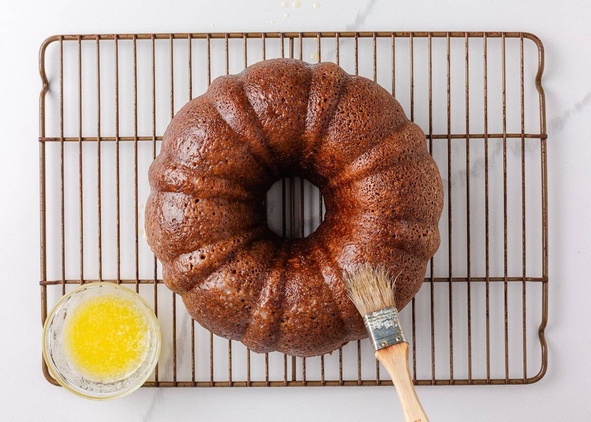 Brushing butter on apple cider donut cake.