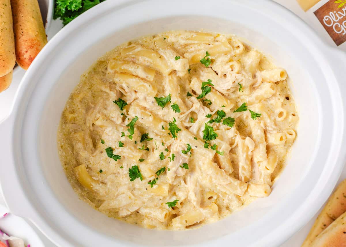Olive Garden chicken pasta combines tender chicken slow-cooked in a rich, creamy, zesty sauce served over your favorite pasta, for the perfect weeknight meal at home! Crockpot Olive Garden chicken pasta with ziti and shredded chicken topped with fresh parsley.