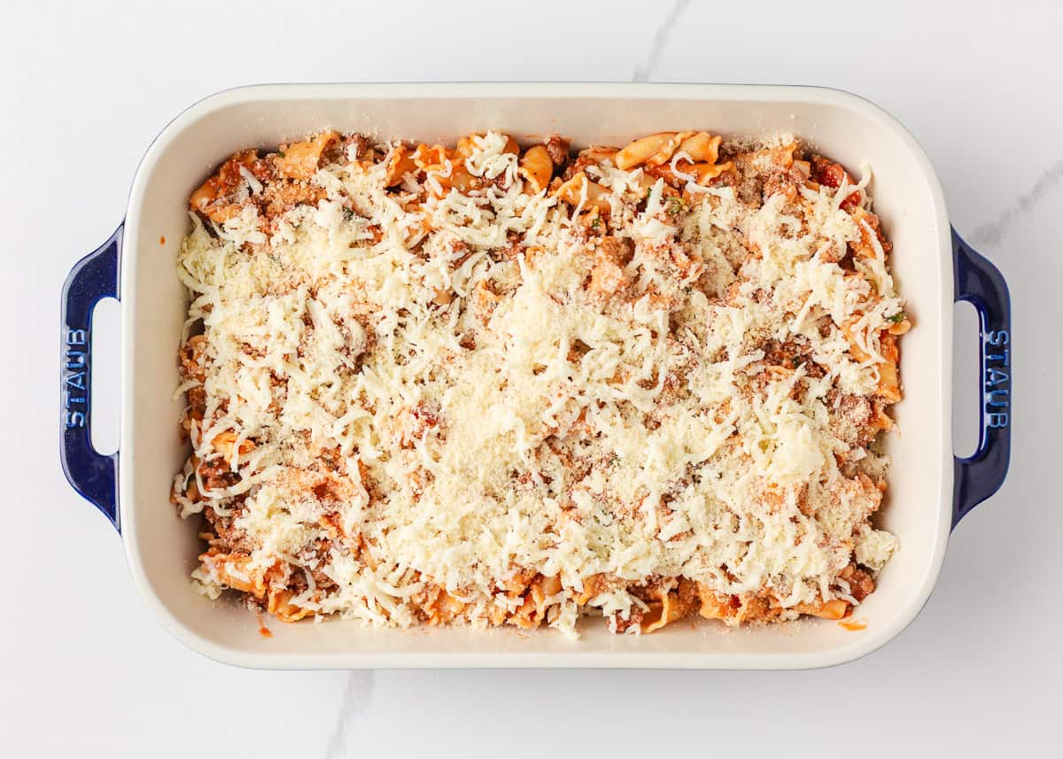 Unbaked lasagna casserole topped with shredded mozzarella and Parmesan cheese, ready to go in the oven.
