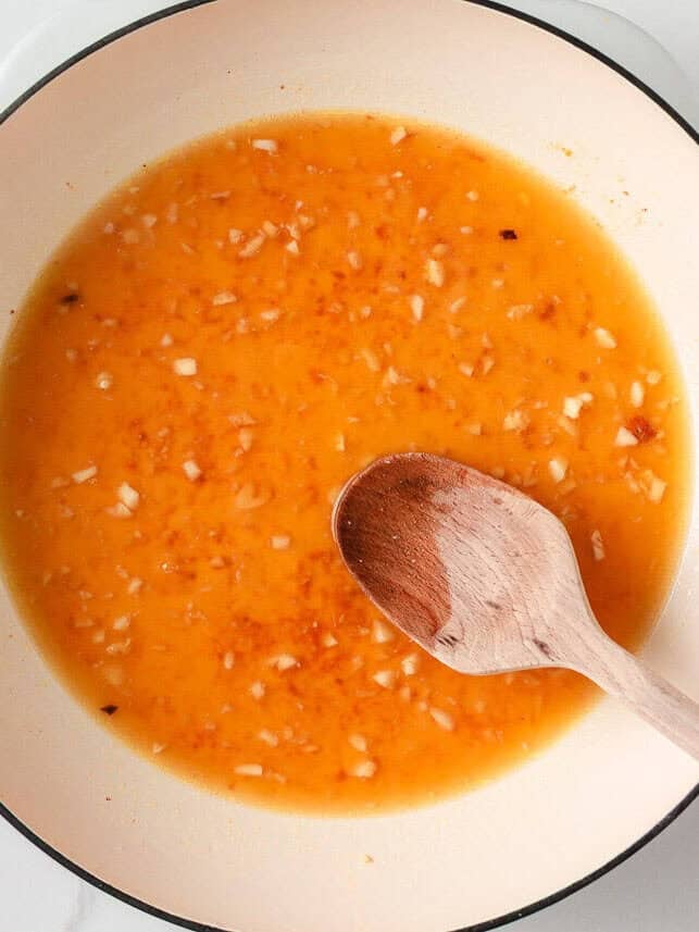 Sauteing garlic with broth in a pan.