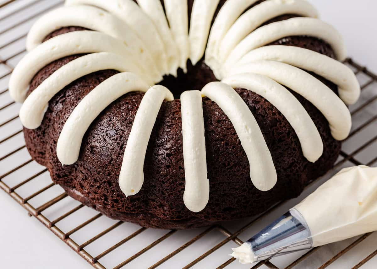 Nothing bundt cake recipe on a wire rack with frosting piping bag.