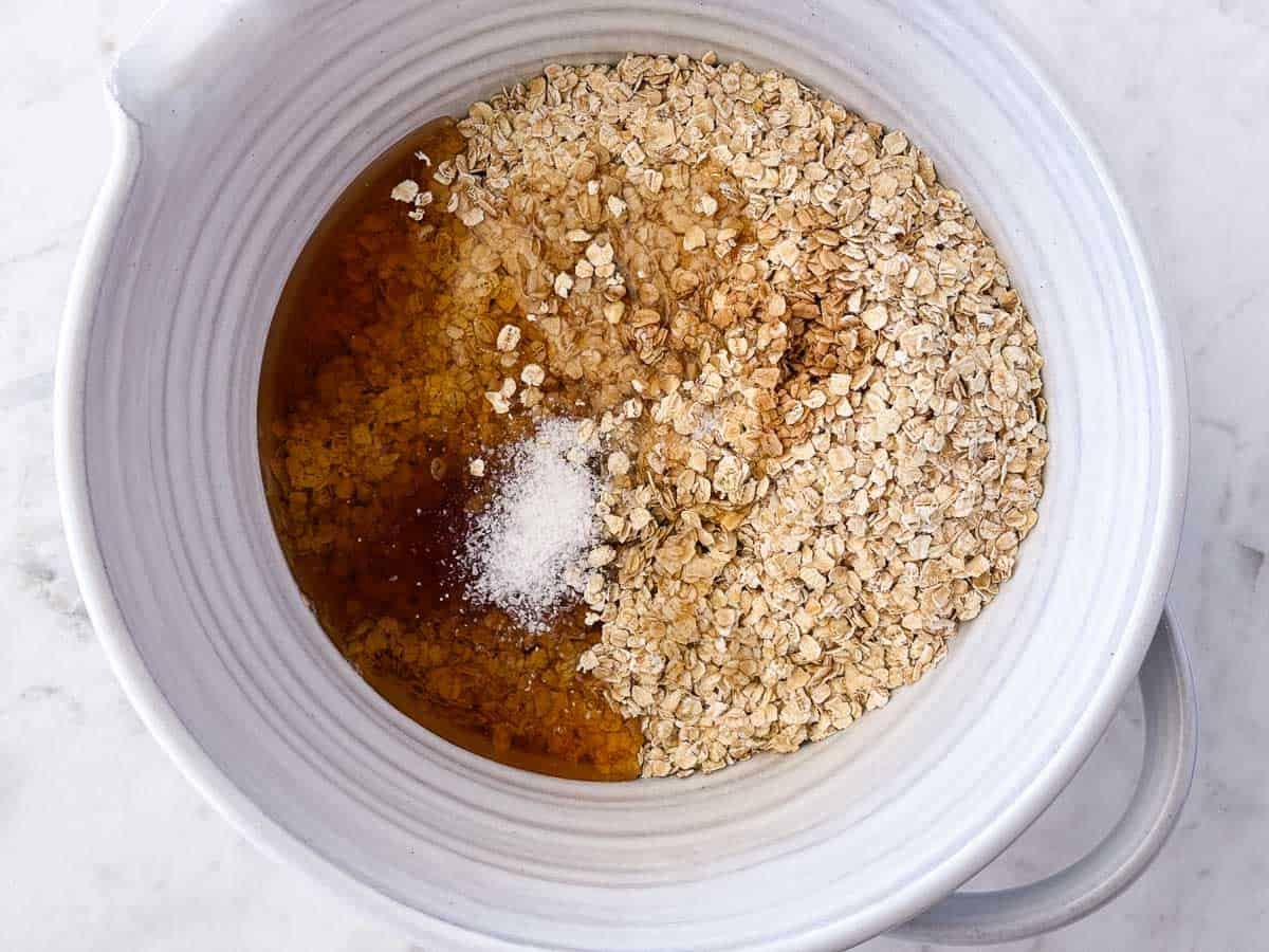 Quick oats, honey, melted coconut oil, salt and vanilla in a bowl to make nut-free granola.