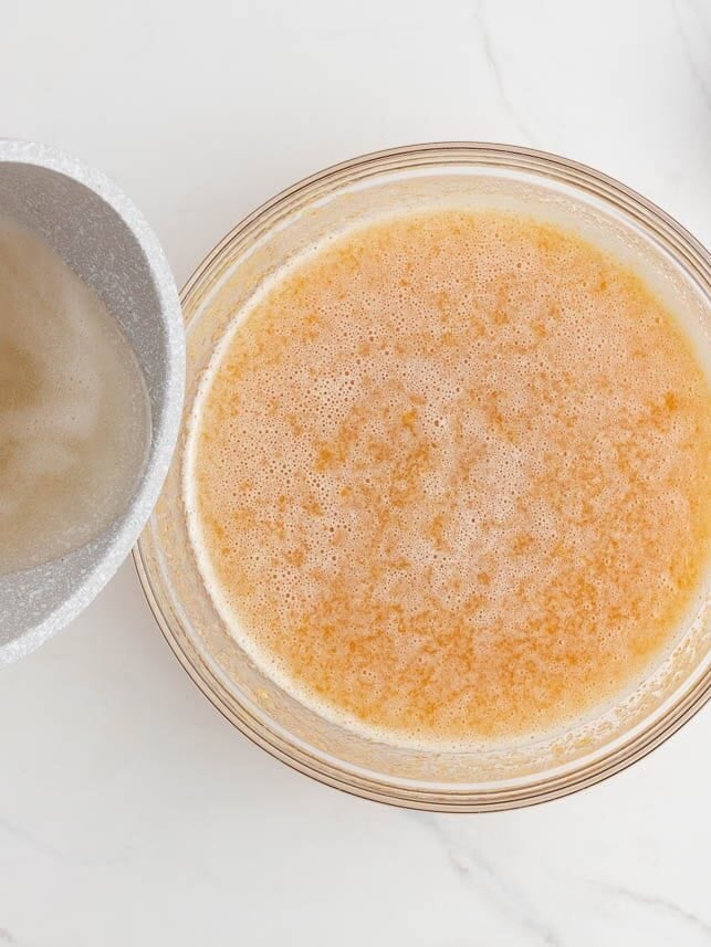 Cooked pectin mixture being added to the peach puree in a bowl.