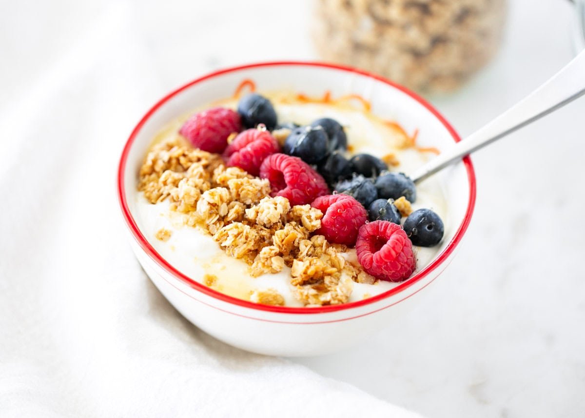 Nut free granola in a bowl with yogurt and berries.