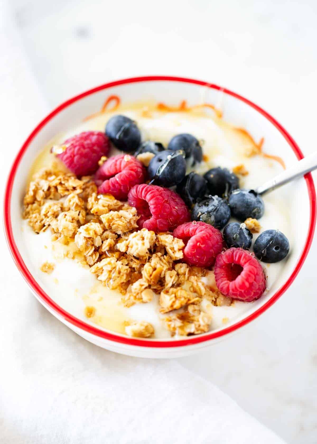 Nut free granola with berries and yogurt in bowl.