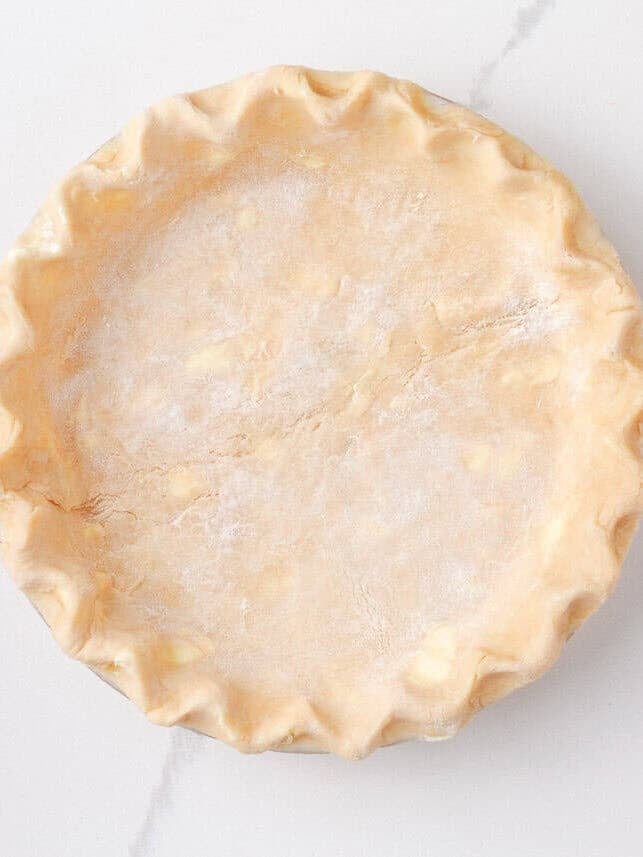 Prepared pie crust pressed into a pie dish, fluted along the edges and ready for the apple filling.