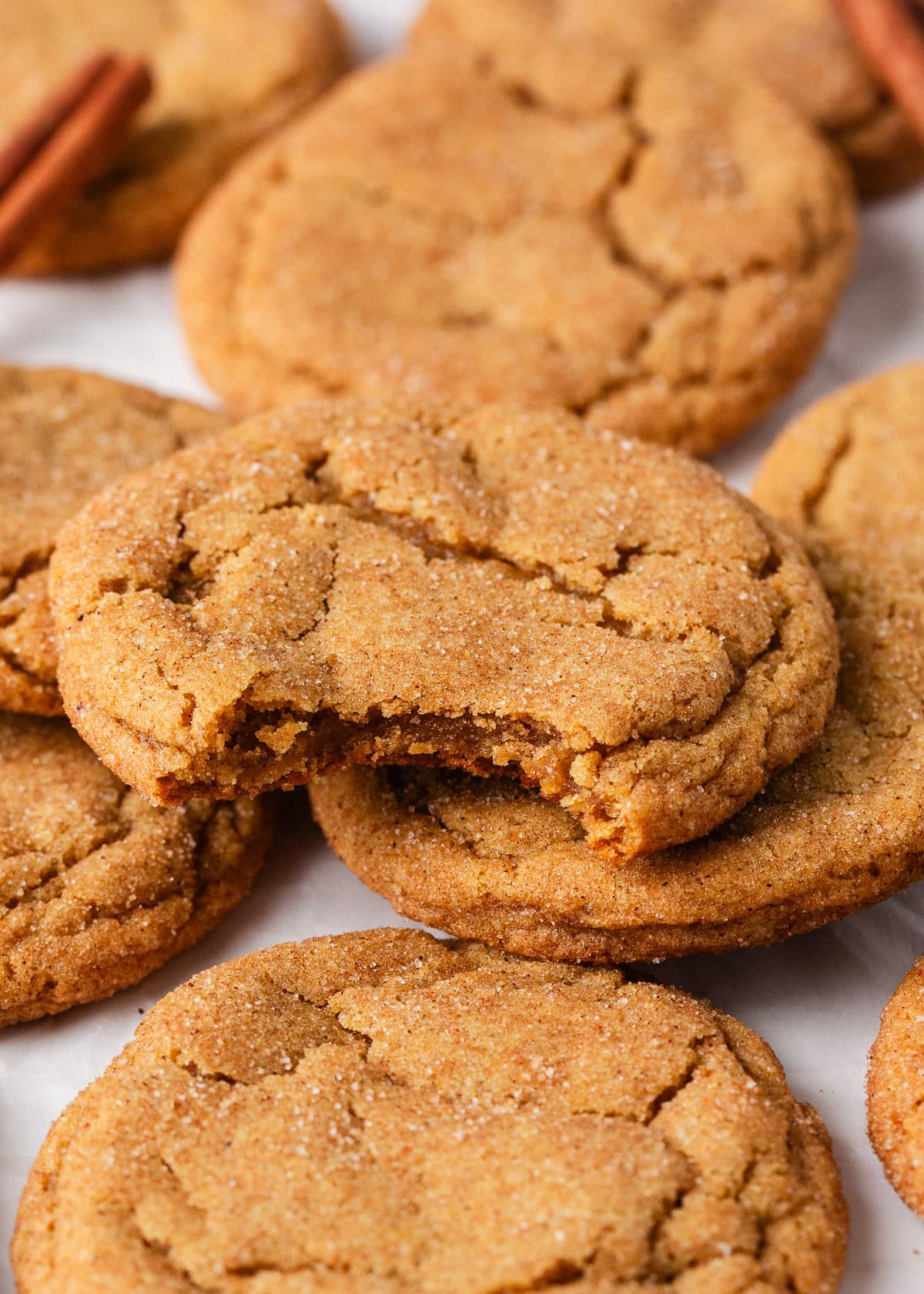 Perfectly spiced and deliciously sweet with the nutty aroma of brown butter, these chewy brown butter pumpkin cookies deliver all the fall coziness in every bite! Soft and chewy pumpkin cookies with cracked tops and cinnamon sugar coating, stacked on parchment.