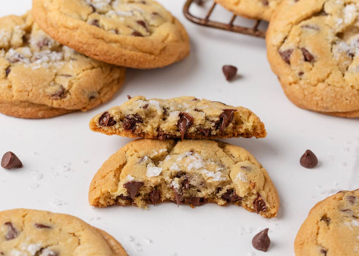 Close-up of Jacque Torres chocolate chip cookies broken in half, showing gooey melted chocolate and flaky sea salt on top.