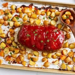 Sheet pan meatloaf with a sweet and tangy glaze plus tender roasted potatoes on a baking pan.