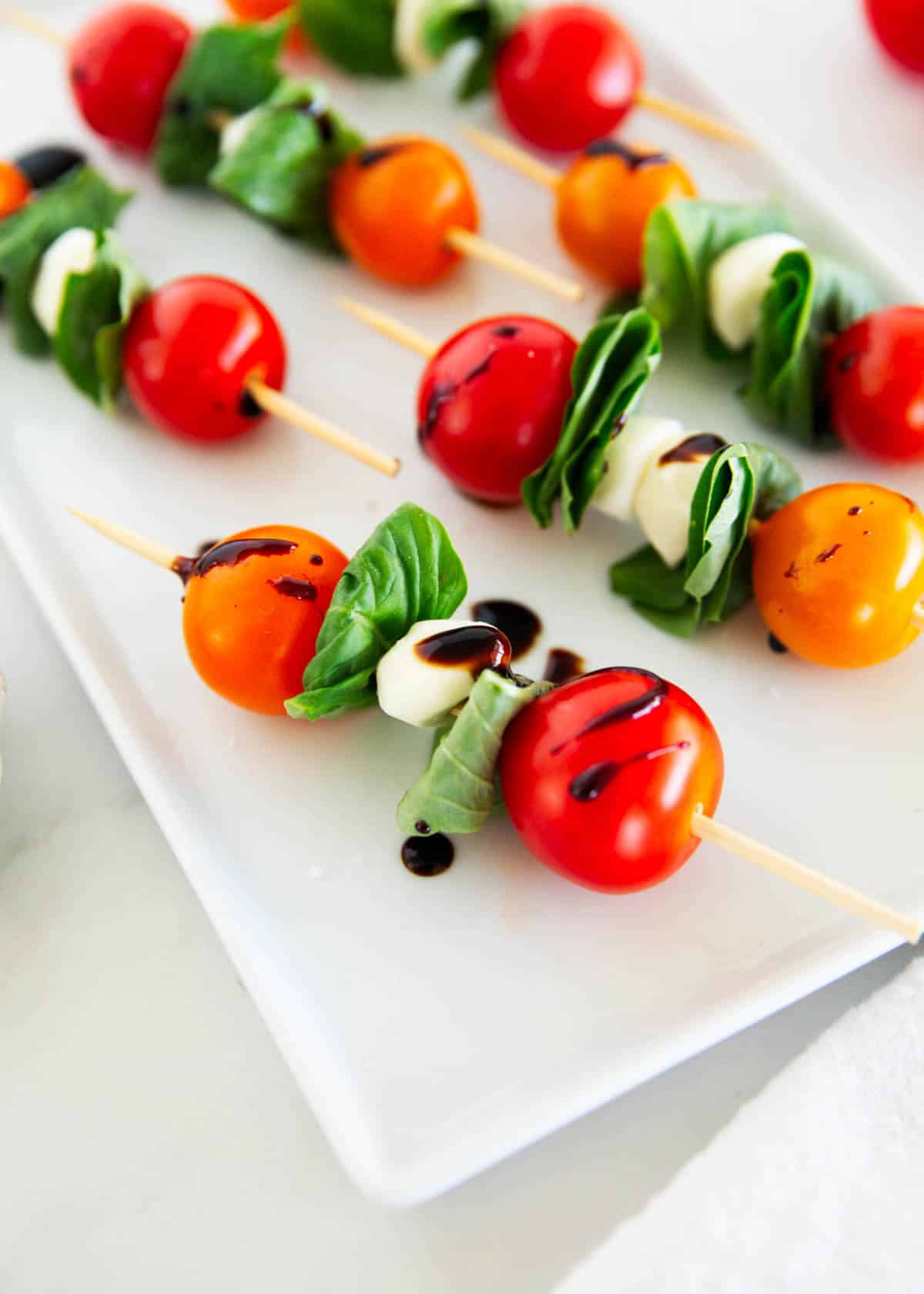 Caprese skewers on a white plate.