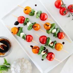 Caprese skewers on a white plate.