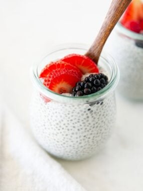 Chia pudding with coconut milk in a glass jar topped with fresh berries.