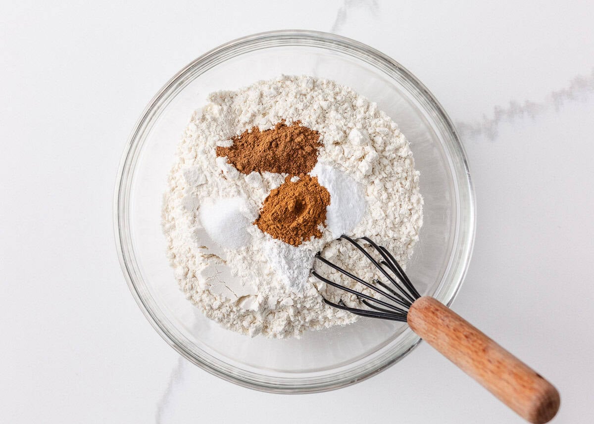 Perfectly spiced and deliciously sweet with the nutty aroma of brown butter, these chewy brown butter pumpkin cookies deliver all the fall coziness in every bite! Dry ingredients including flour, baking soda, cinnamon, and pumpkin spice added to a bowl, ready to be whisked together.