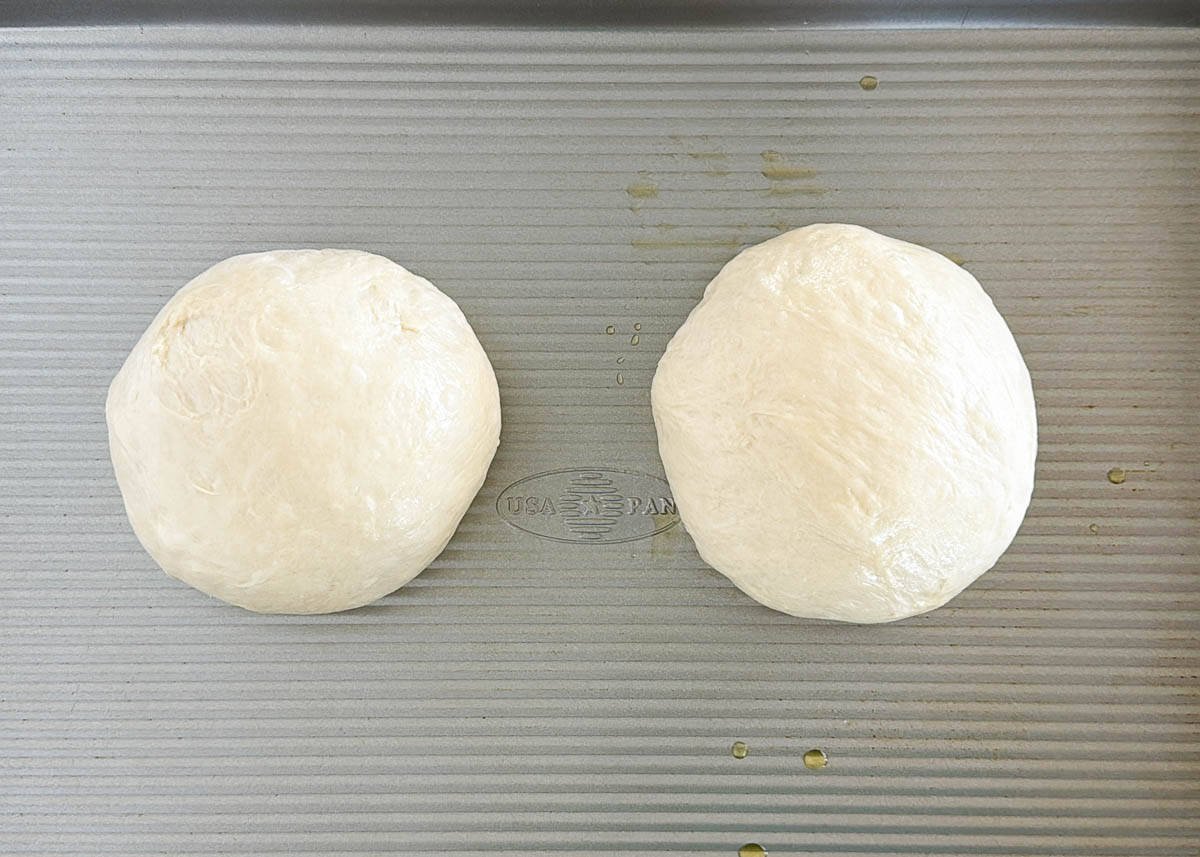 Two dough balls on a pan for margherita pizza.