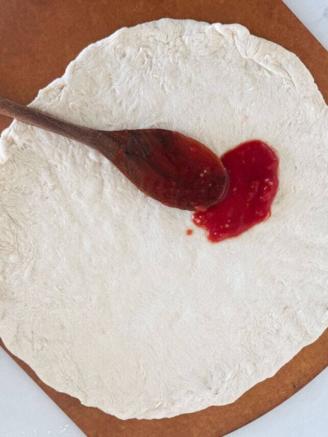 Spreading sauce onto pizza dough.