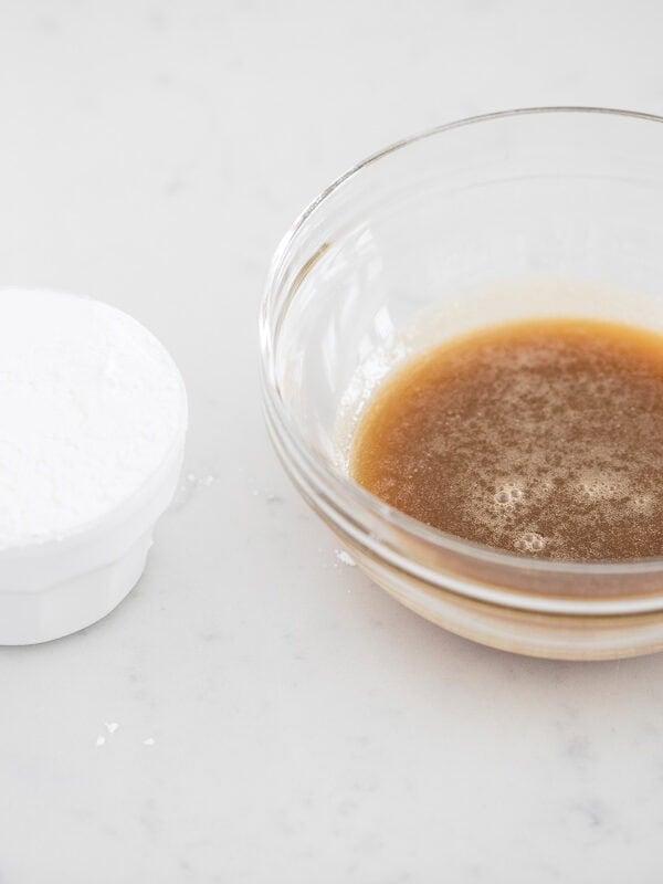 Powdered sugar next to a bowl of warm caramel mixture, ready to be whisked together for the icing.