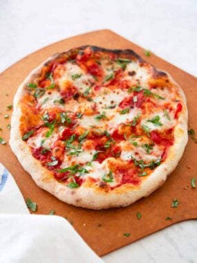 Margherita pizza on a wooden peel topped with fresh basil.