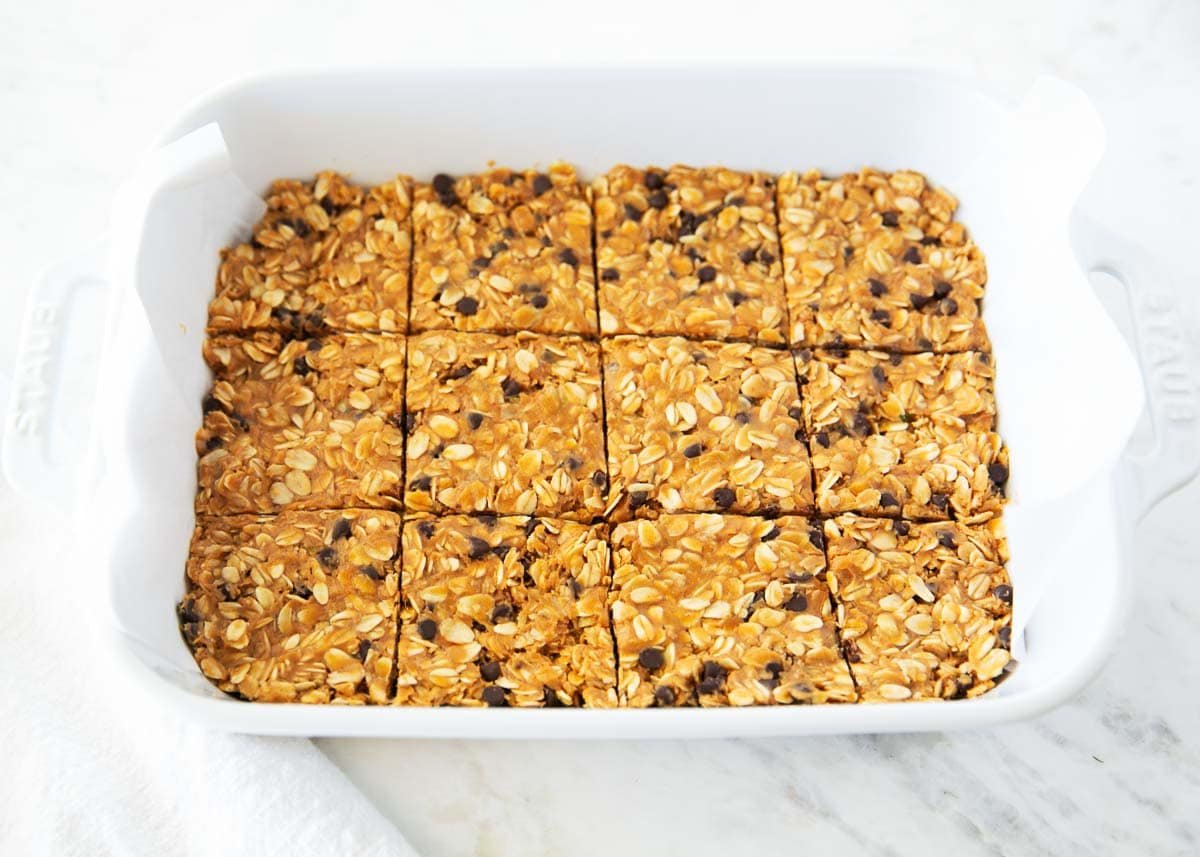 These chewy peanut butter oatmeal bars are an easy no-bake snack, breakfast or healthy dessert made with simple ingredients like peanut butter, oats, and honey! No bake peanut butter oatmeal bars cut into squares in a white baking dish lined with parchment paper.
