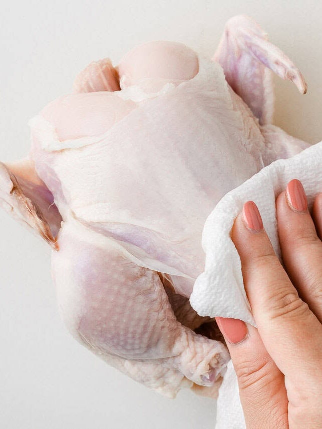 Using a paper towel to pat Cornish game hen dry.