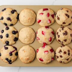 Pancake muffins in a muffin tin with blueberry, strawberries and chocolate chips.