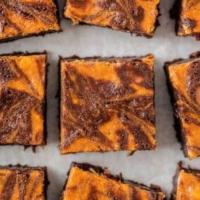 Overhead view of pumpkin brownies cut into squares with a marbled pumpkin and chocolate swirl pattern.