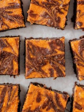 Overhead view of pumpkin brownies cut into squares with a marbled pumpkin and chocolate swirl pattern.