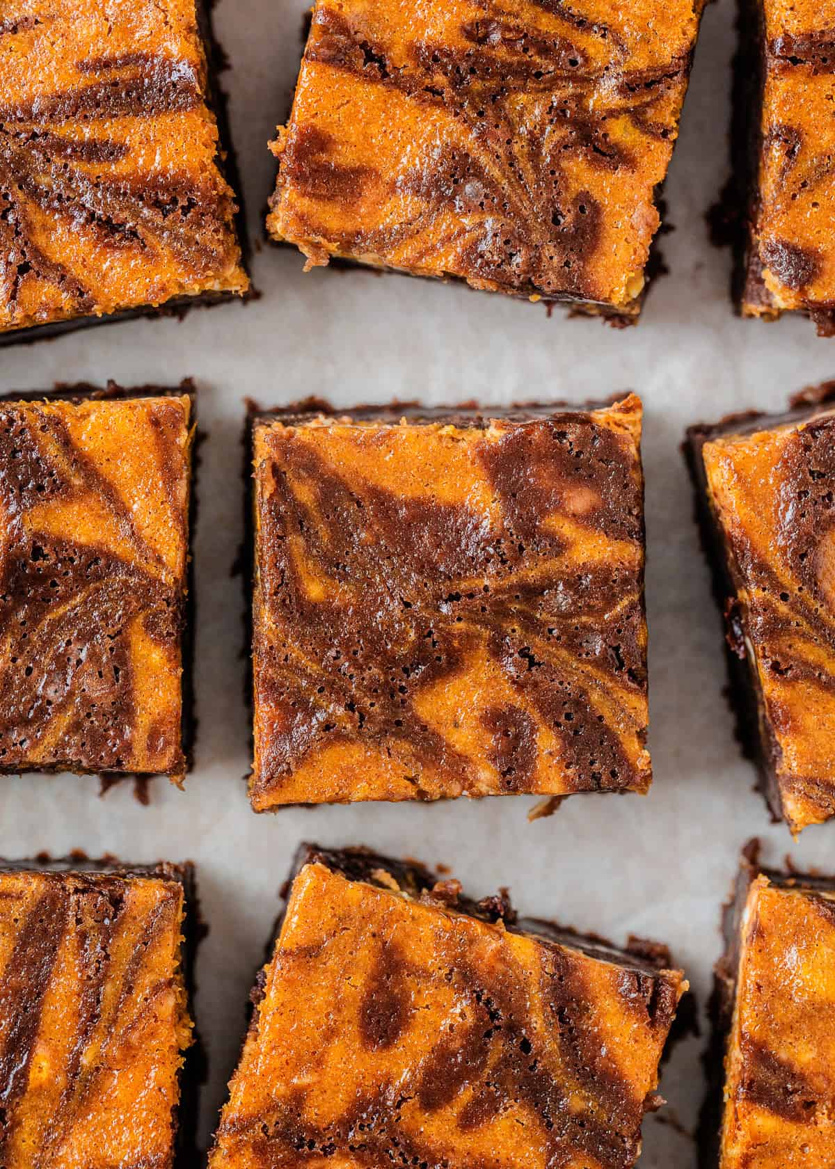 Overhead view of pumpkin brownies cut into squares with a marbled pumpkin and chocolate swirl pattern.