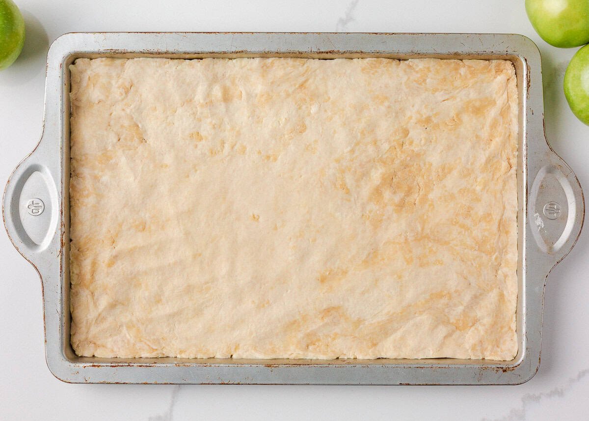 Pastry dough pressed into a sheet pan for slab apple pie.