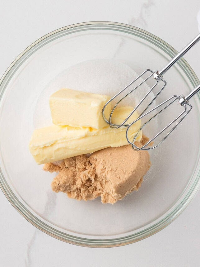 Creaming butter, brown sugar, and granulated sugar in a glass bowl with a hand mixer to start the best banana cake batter.