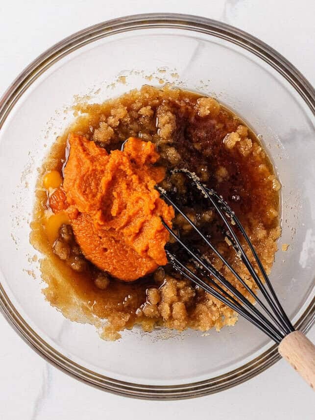 Perfectly spiced and deliciously sweet with the nutty aroma of brown butter, these chewy brown butter pumpkin cookies deliver all the fall coziness in every bite! Whisking together brown sugar, pumpkin purée, egg, maple syrup, brown butter and vanilla in a glass bowl to begin making the cookie dough base.