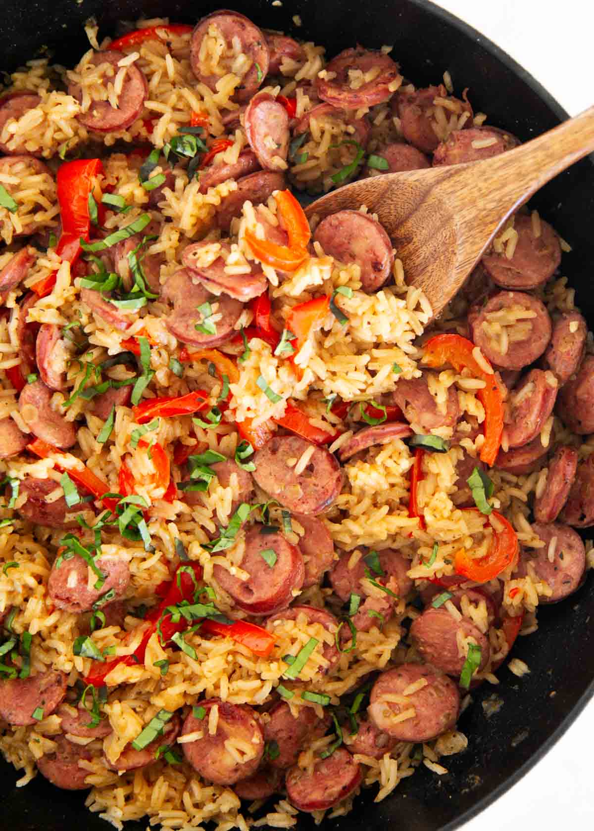 This sausage and rice skillet is the perfect one-pan dinner for busy weeknights packed with savory sausage, rice, and tender veggies! It's a hearty meal the whole family will love. One pot sausage and rice skillet with smoked sausage, bell peppers, and fluffy rice topped with fresh herbs.