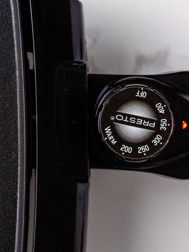 Close-up of electric griddle temperature dial set to 350 degrees for cooking French toast.
