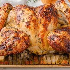 Crispy oven roasted spatchcock turkey resting on a sheet pan with vegetables.