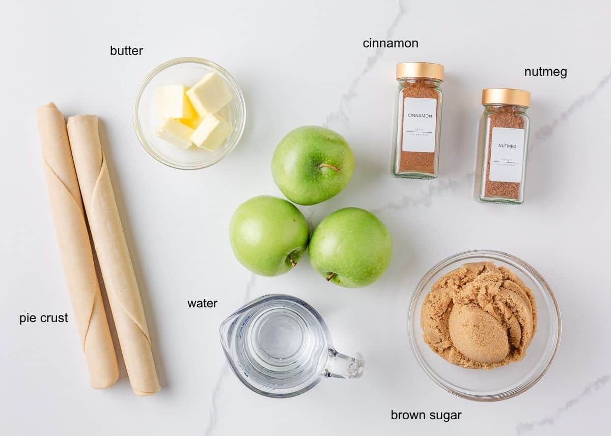 Apple dumpling ingredients including pie dough, brown sugar, butter, apples and warm spices.