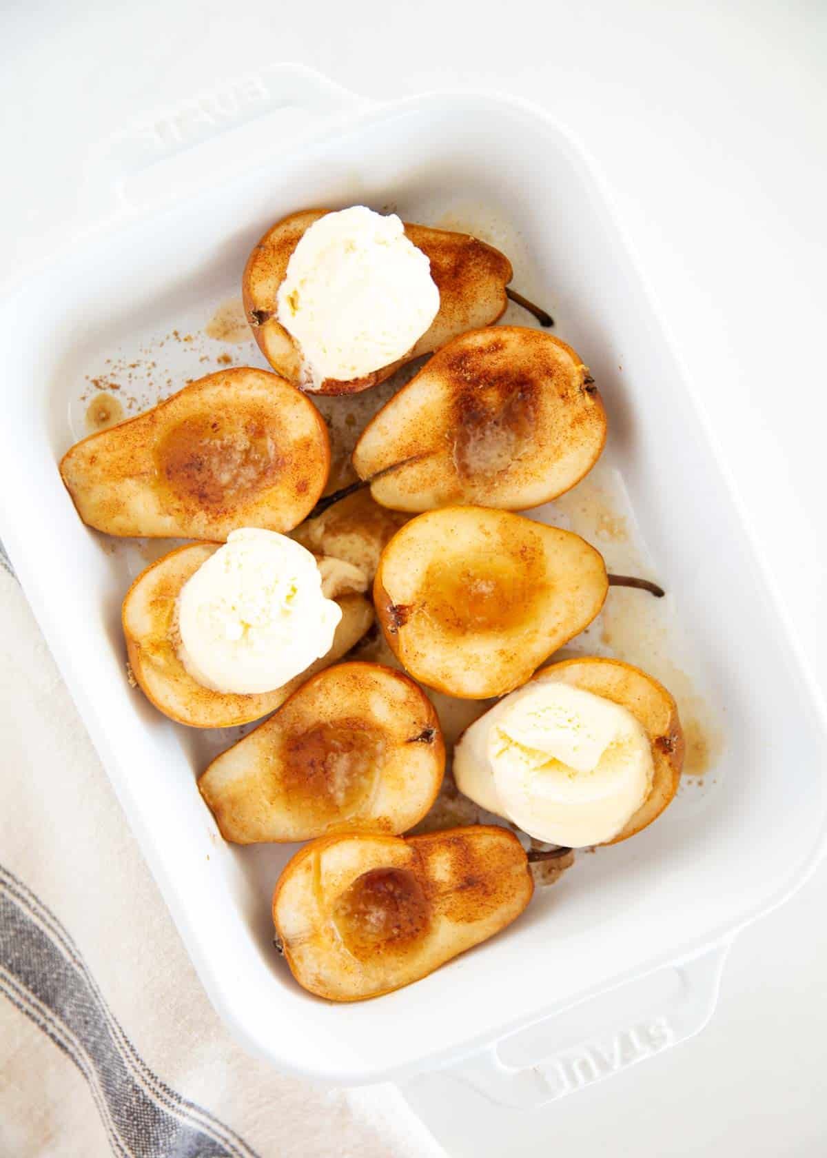 Baked pears with scoops of vanilla ice cream melting over the top, a quick baked pear dessert idea.