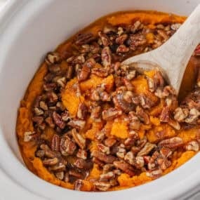 Crockpot sweet potato casserole with brown sugar pecan topping and wooden spoon.