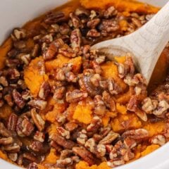 Crockpot filled with sweet potato casserole and crunchy pecan topping.