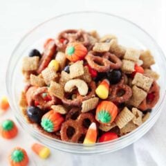 Bowl of fall Chex mix with candy corn, mellowcreme pumpkins, pretzels, and salted cashews .