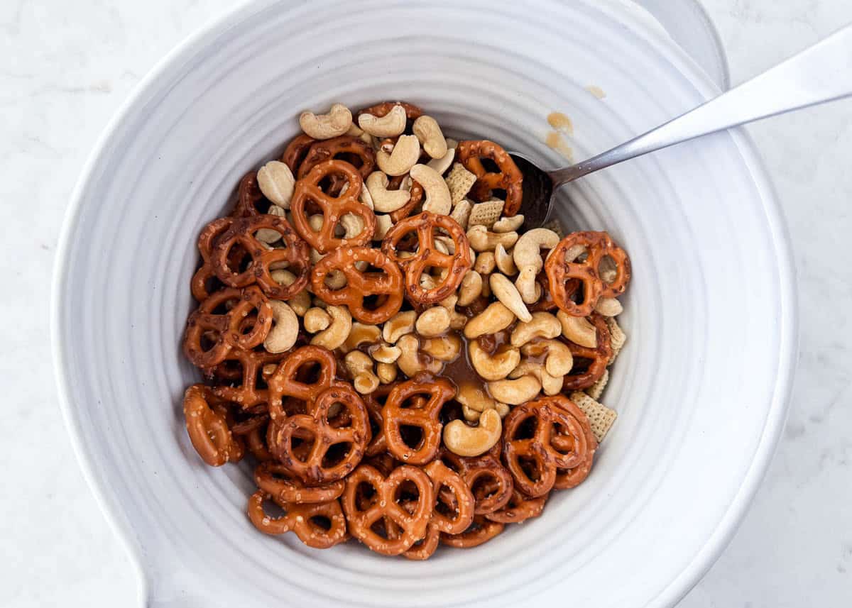Mixing bowl with pretzels, cashews, and Chex cereal coated in brown sugar and butter.