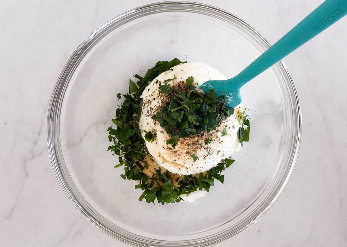 Frozen cheese ravioli in a skillet topped with dollops of ricotta and parsley cheese mixture.