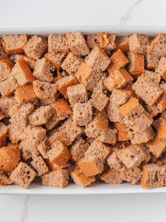 Spice cake cut into cubes in a white baking dish, ready for layering in a pumpkin trifle.